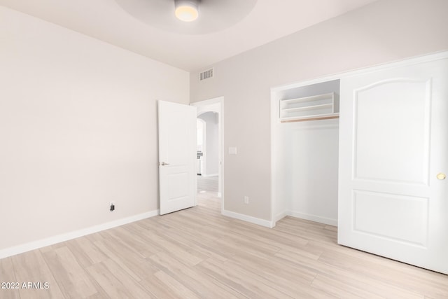 unfurnished bedroom featuring a closet, light hardwood / wood-style flooring, and ceiling fan