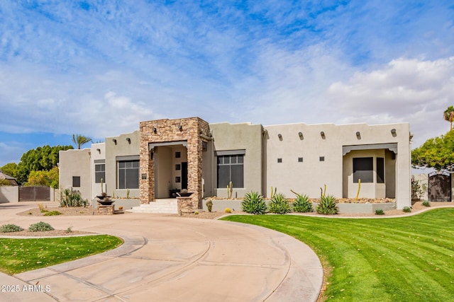 southwest-style home with stucco siding, a front yard, and a gate