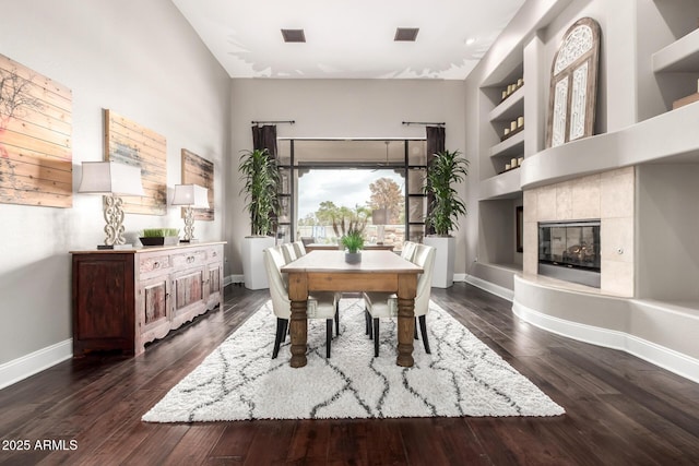 dining space with dark wood-type flooring, built in shelves, visible vents, and baseboards