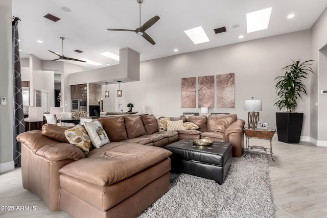 living area with visible vents, recessed lighting, a skylight, baseboards, and ceiling fan