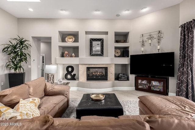 living room with a glass covered fireplace, built in features, and recessed lighting