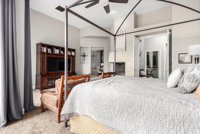 bedroom featuring light carpet, visible vents, a fireplace, and a ceiling fan