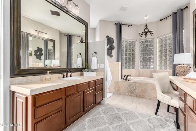 full bath featuring visible vents, a garden tub, an inviting chandelier, and vanity