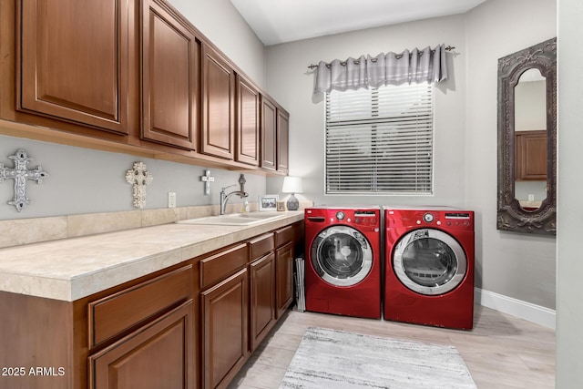 laundry area with a sink, cabinet space, baseboards, and separate washer and dryer