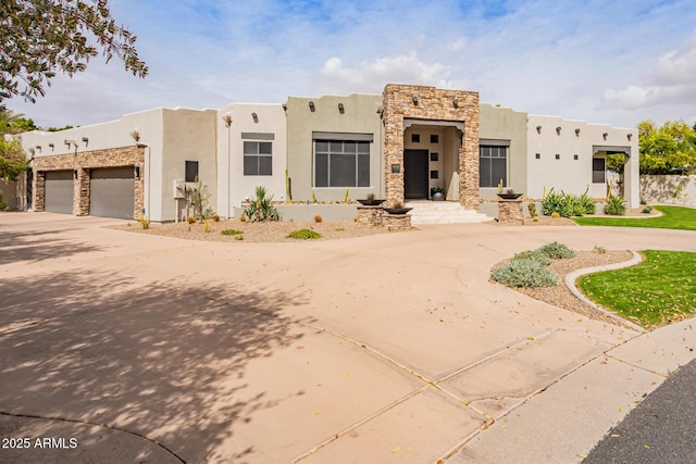 southwest-style home with stucco siding, an attached garage, stone siding, and curved driveway