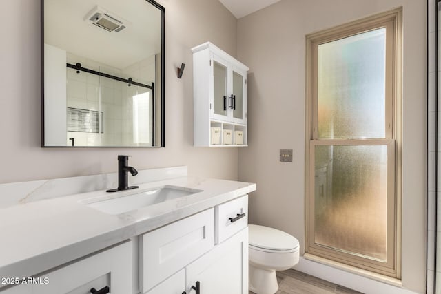 bathroom featuring toilet, walk in shower, and vanity