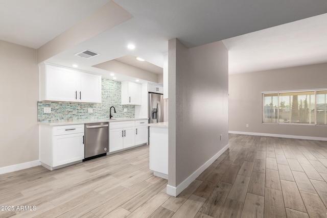 kitchen with tasteful backsplash, light hardwood / wood-style floors, sink, stainless steel appliances, and white cabinets