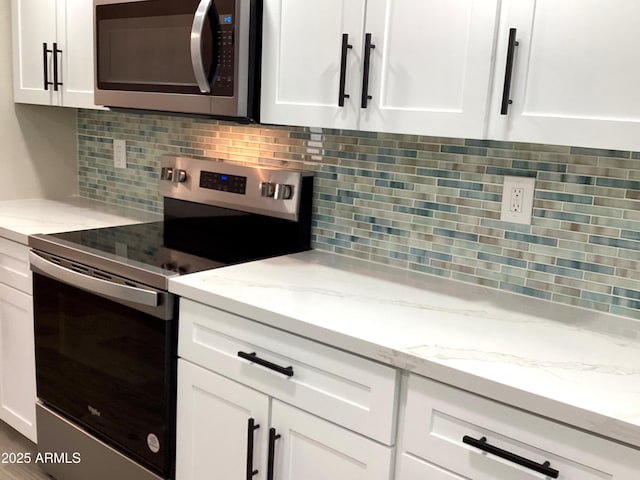 kitchen with appliances with stainless steel finishes, white cabinets, tasteful backsplash, and light stone countertops