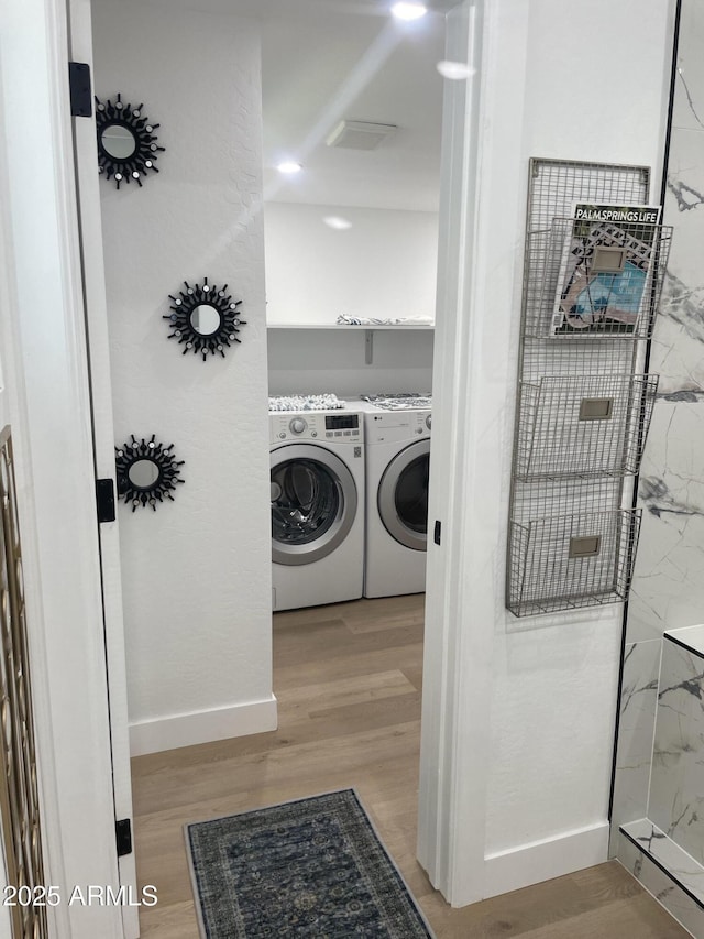 clothes washing area with laundry area, visible vents, light wood finished floors, and washer and dryer