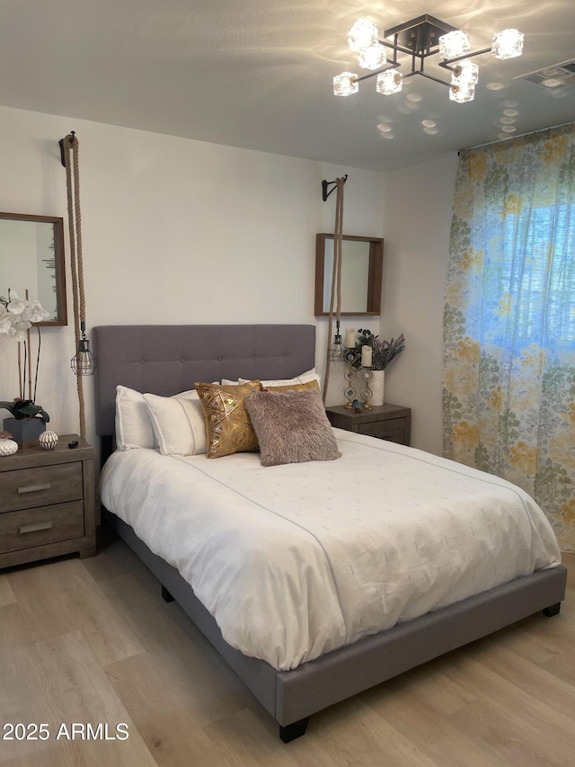bedroom featuring a chandelier, wood finished floors, and visible vents