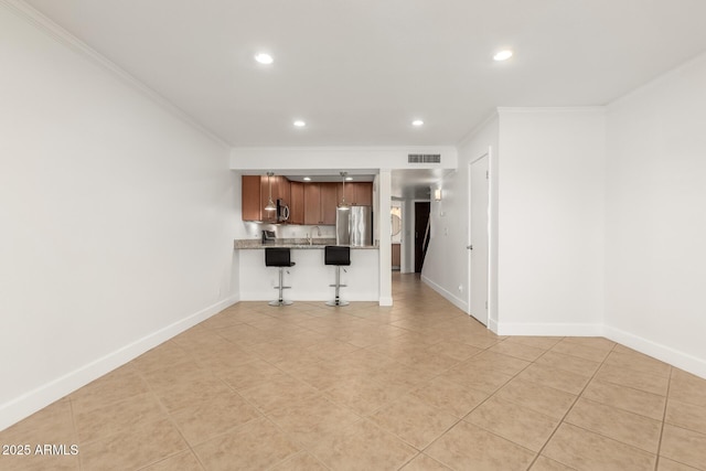 kitchen featuring stainless steel appliances, crown molding, a breakfast bar, and light tile patterned floors