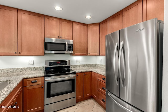 kitchen featuring light stone counters, appliances with stainless steel finishes, and light tile patterned floors