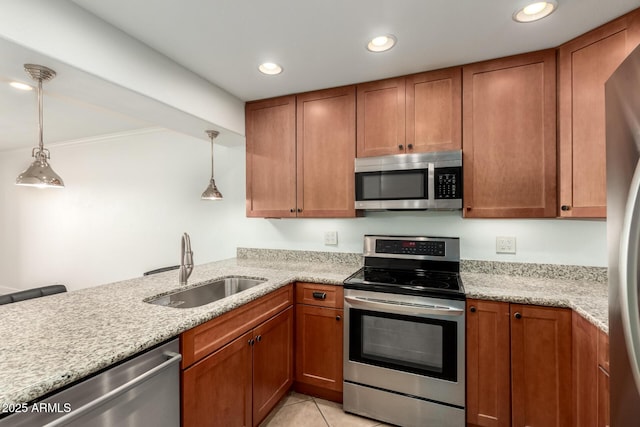 kitchen featuring stainless steel appliances, light stone countertops, sink, and decorative light fixtures