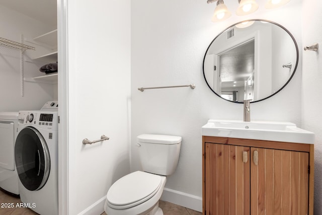 bathroom featuring tile patterned flooring, vanity, washing machine and clothes dryer, and toilet