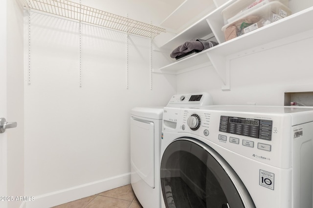 clothes washing area featuring light tile patterned flooring and washer and dryer