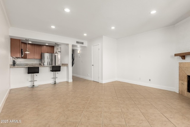 unfurnished living room featuring ornamental molding, sink, light tile patterned floors, and a fireplace