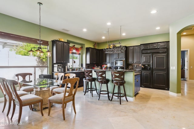 6428 W Eugie Ave, Glendale, AZ 85304 - kitchen with built in appliances, a kitchen island, a kitchen breakfast bar, backsplash, and dark countertops