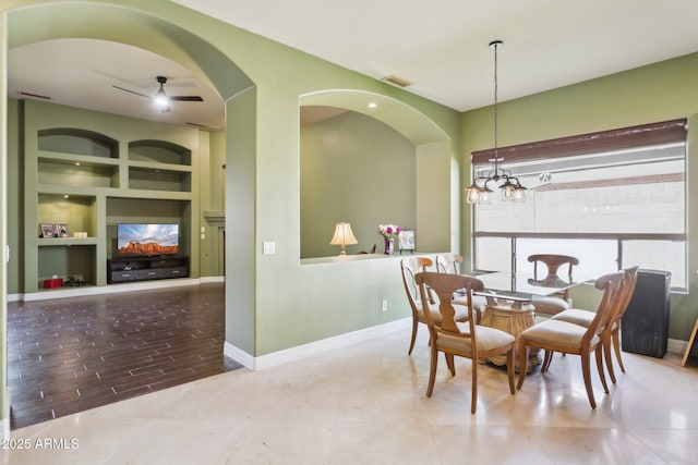 6428 W Eugie Ave, Glendale, AZ 85304 - dining area featuring a fireplace, built in features, arched walkways, ceiling fan, and a chandelier