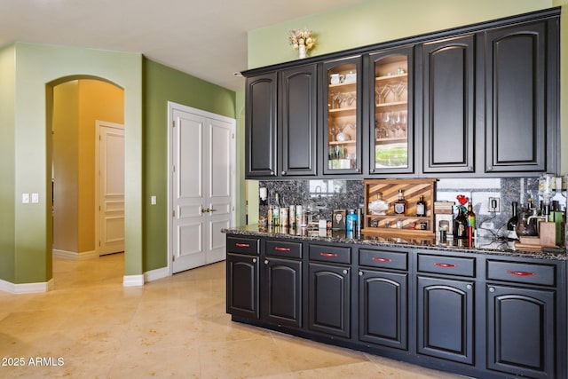 6428 W Eugie Ave, Glendale, AZ 85304 - indoor bar featuring arched walkways, decorative backsplash, baseboards, and light tile patterned flooring