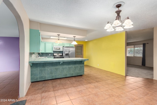 kitchen featuring kitchen peninsula, backsplash, appliances with stainless steel finishes, light tile patterned flooring, and decorative light fixtures