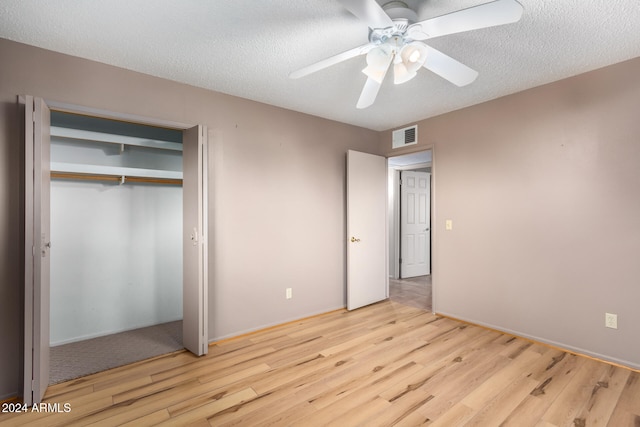 unfurnished bedroom featuring a closet, a textured ceiling, light wood-type flooring, and ceiling fan