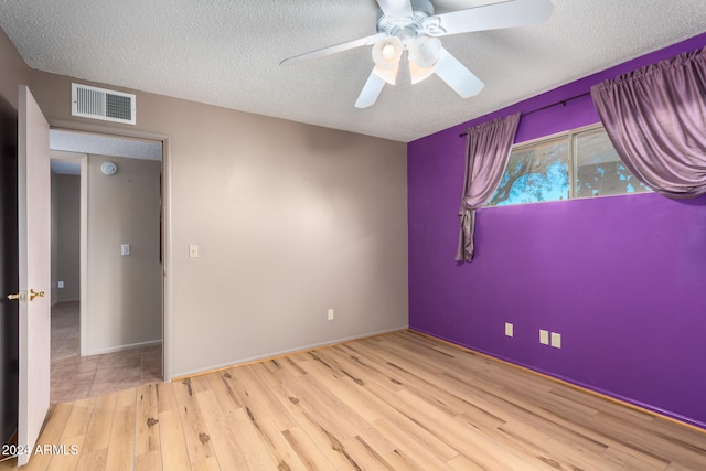 empty room with a textured ceiling, light wood-type flooring, and ceiling fan