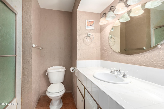 bathroom with walk in shower, vanity, toilet, and tile patterned flooring