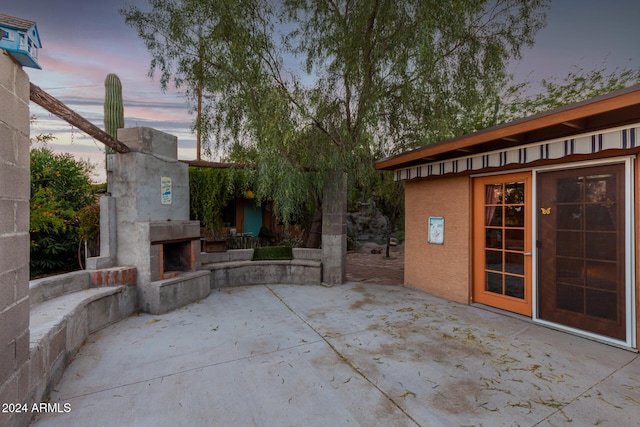 patio terrace at dusk featuring an outdoor stone fireplace