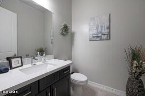 bathroom with baseboards, toilet, and vanity