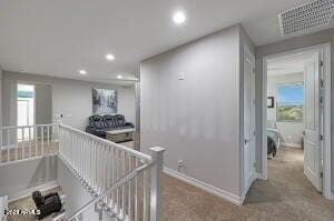corridor with an upstairs landing, visible vents, and recessed lighting