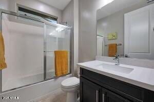 bathroom featuring bath / shower combo with glass door, toilet, and vanity