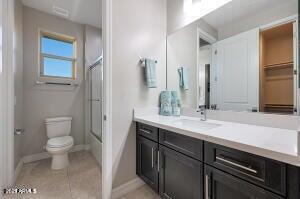 full bathroom featuring vanity, toilet, combined bath / shower with glass door, baseboards, and tile patterned flooring