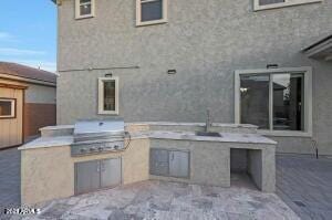 view of patio featuring an outdoor kitchen, area for grilling, and a sink