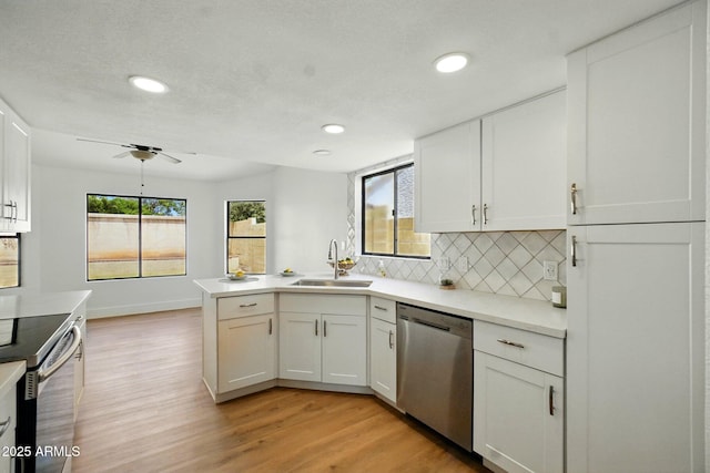 kitchen with a sink, light wood-type flooring, white cabinetry, backsplash, and appliances with stainless steel finishes