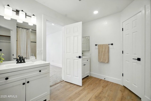 full bath featuring baseboards, wood finished floors, recessed lighting, and vanity