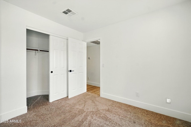 unfurnished bedroom featuring baseboards, carpet flooring, visible vents, and a closet