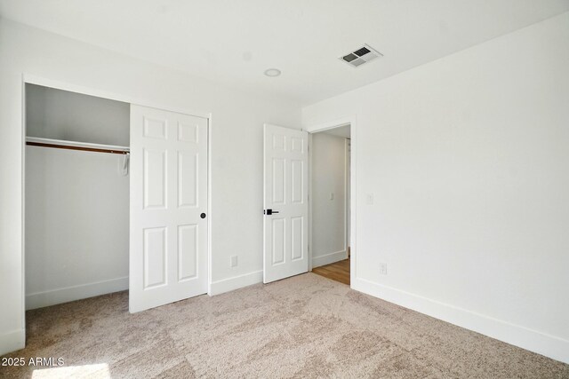 unfurnished bedroom featuring baseboards, visible vents, carpet floors, and a closet