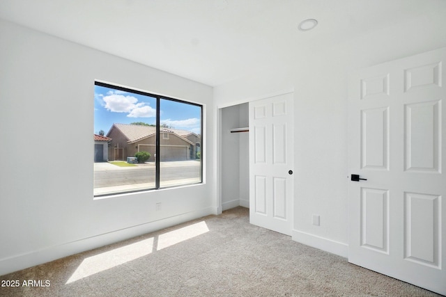 unfurnished bedroom featuring baseboards, carpet floors, and a closet