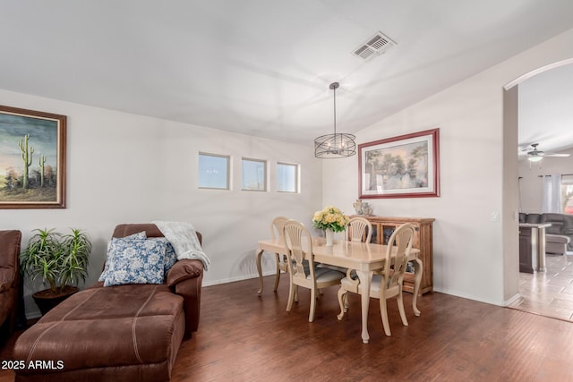 dining area with lofted ceiling, dark wood-type flooring, and ceiling fan with notable chandelier