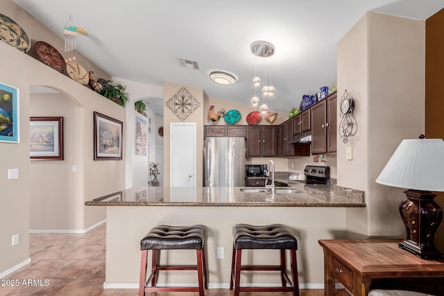 kitchen featuring sink, hanging light fixtures, dark brown cabinetry, kitchen peninsula, and stainless steel appliances