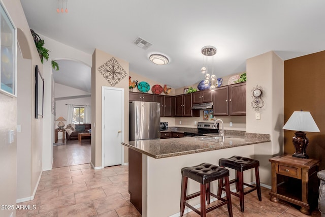 kitchen featuring lofted ceiling, dark brown cabinets, kitchen peninsula, pendant lighting, and stainless steel appliances