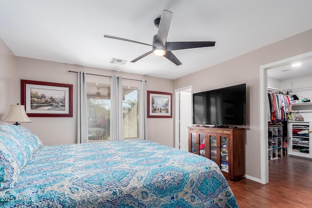 bedroom with ceiling fan, dark hardwood / wood-style floors, and a spacious closet