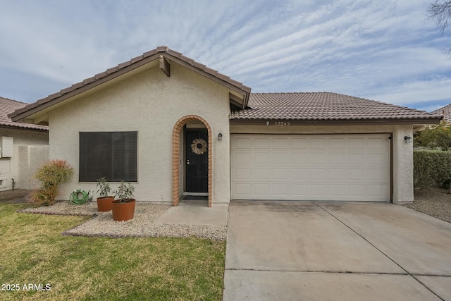 view of front of property with concrete driveway, an attached garage, a tile roof, and stucco siding