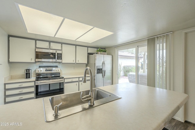 kitchen featuring stainless steel appliances, a sink, and light countertops