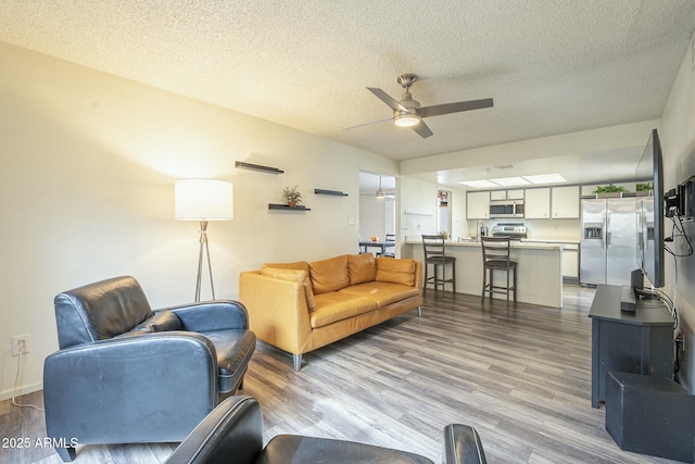 living room featuring ceiling fan, a textured ceiling, and wood finished floors