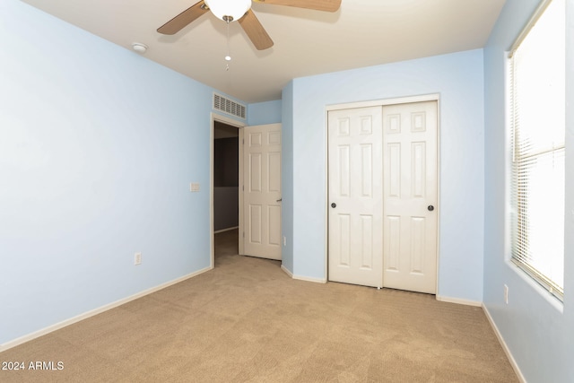 unfurnished bedroom featuring ceiling fan, a closet, and light colored carpet