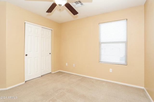 unfurnished bedroom with ceiling fan, light carpet, and a closet