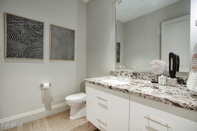 bathroom with toilet, baseboards, wood finished floors, and vanity