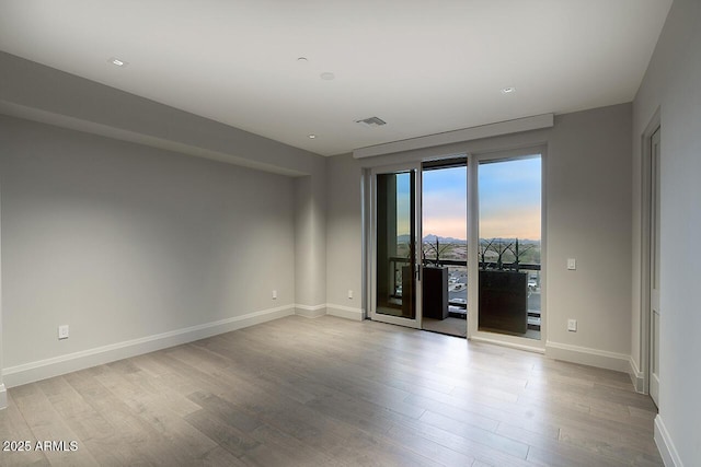 empty room featuring visible vents, baseboards, and wood finished floors