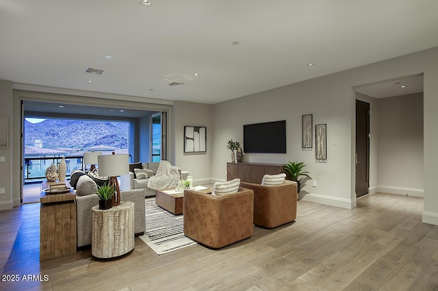 living area featuring light wood finished floors, visible vents, and baseboards